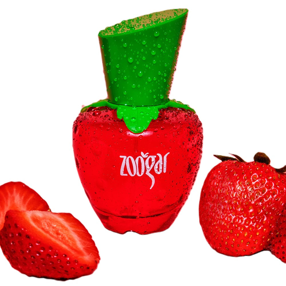 A bottle of ZOOGAR JAFRA PERFUME DE MUJER with a green cap, alongside a halved red strawberry, both against a white background. SOLO EN OBSEQUIOSVERO