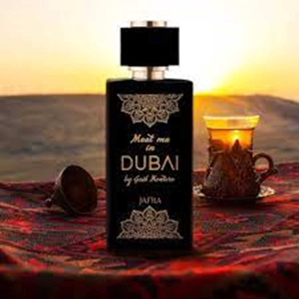 Perfume bottle labeled 'Meet me in Dubai' on a table with a sunset background
